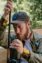 A focused fisherman carefully sets up his fishing rod outdoors in a natural setting.